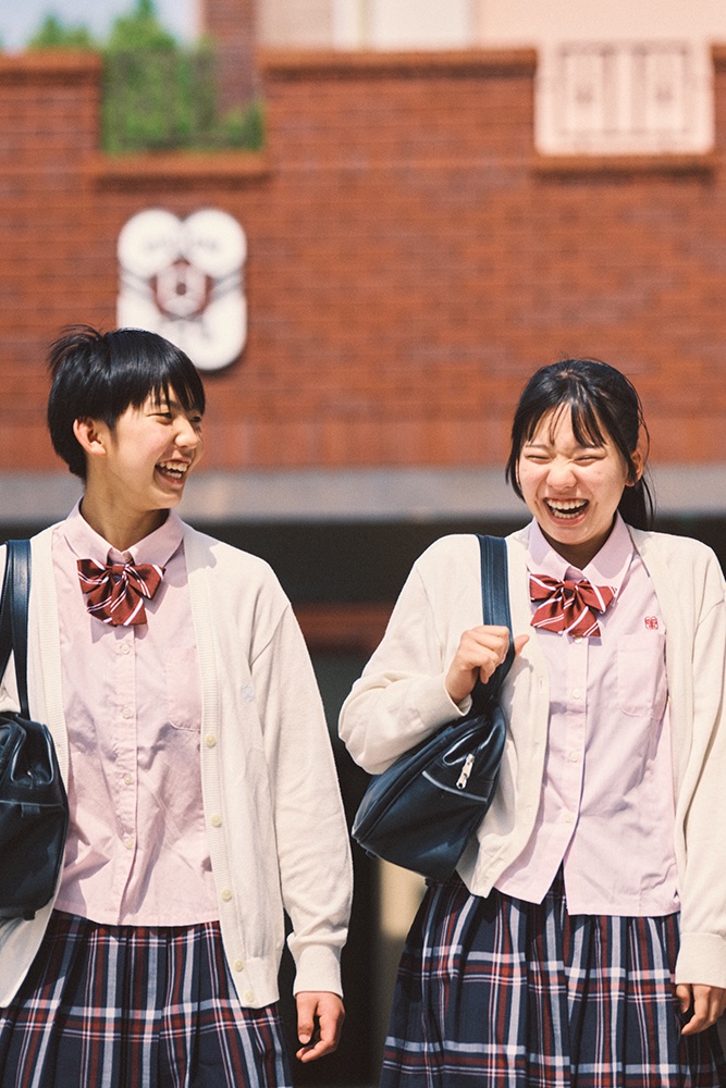 窓辺で笑顔を見せる制服姿の生徒