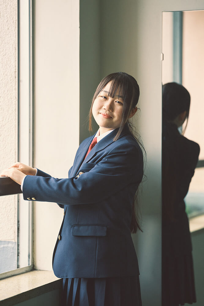 窓辺に立つ制服姿の生徒