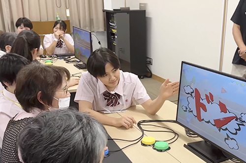 ゲーム画面を示しながら地域の方と交流する生徒