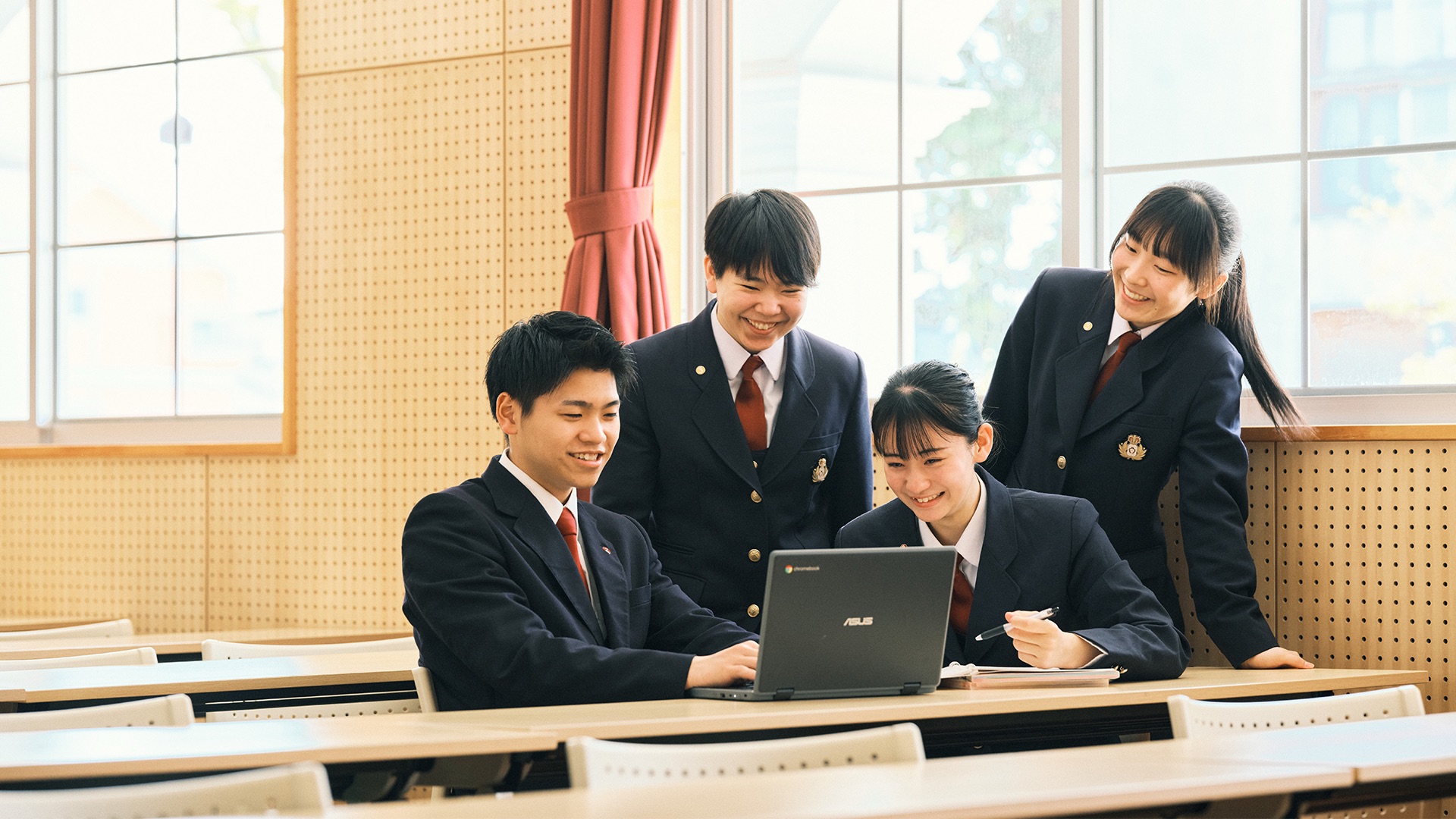 教室でパソコンを囲み、一緒に学ぶ生徒たち