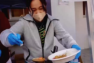 菊女フェスタのバザーで料理を皿に盛り付ける様子